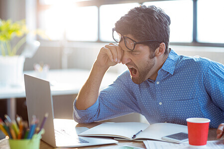 Tired man yawning at work